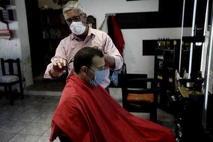 Héctor corta el pelo en su comercio, en el primer día del regreso a la actividad en Benito Juárez