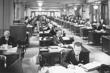 Sin cubículos y con los escritorios dispuestos simétricamente, una oficina de los años 30