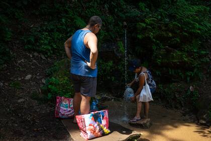 Sin servicio eléctrico, los vecinos de la Rocinha se proveen de agua en vertientes naturales (Photo by Tercio TEIXEIRA / AFP)