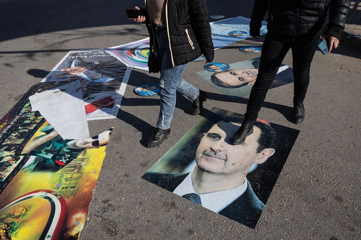 Sirios caminan sobre posters del derrocado Bashar al-Assad y su padre, Hafez al-Assad, en Homs. (David Guttenfelder/The New York Times)