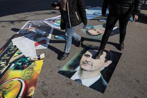 Sirios caminan sobre posters del derrocado Bashar al-Assad y su padre, Hafez al-Assad, en Homs. (David Guttenfelder/The New York Times)