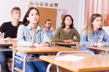 Smiling schoolgirl is learning and answering the question on paper in the class.