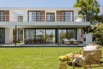 Sobre el césped, sillones de mimbre (Akelik) y fanales (Dukaan Home).