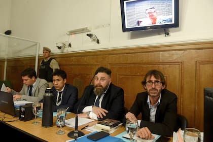 Sobre el grupo de defensores, la pantalla muestra a Guille Cantero, que siguió el juicio mediante una videoconferencia