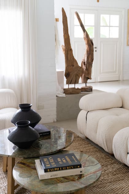 Sobre el piso, en la entrada, tótem de madera quemada y cerámicas negras sobre las mesas de centro, y alfombra de yute, todo de Gloria Atelier Deco, tienda que la asesoró con la disposición de los muebles y el interiorismo.