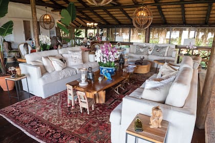 Sobre la alfombra persa del living principal descansa una mesa baja de cedro del Paraguay. Las sillas pequeñas fueron traídas por la dueña de casa desde la India y las lámparas de madera son de Tailandia. Las orquídeas que decoran los ambientes en divinos jarrones y macetas son cultivadas en el campo de Laetitia.