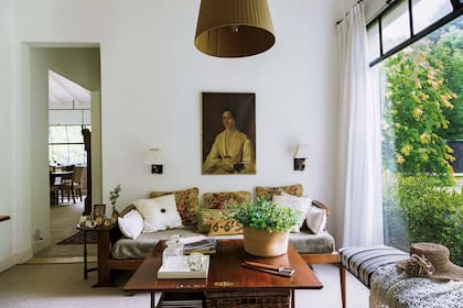 Sobre la mesa de madera, canasto con plantas silvestres y bandeja blanca (Reina Batata) con jarras de vidrio.