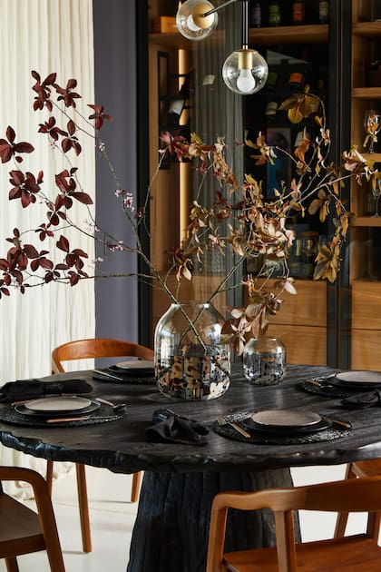 Sobre la mesa de madera quemada, vajilla negra de Dukaan Home.