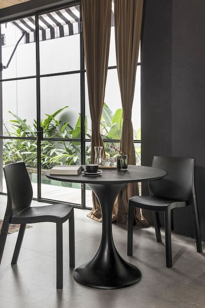 Sobre la mesa ‘Tulip’ en riguroso negro, florero ‘Dito’ de vidrio soplado con ramitas de durazno en flor (The Linen Store).