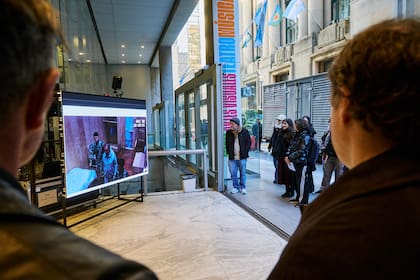 Sobre la pantalla, una cámara filma al público que se concentra en Buenos Aires