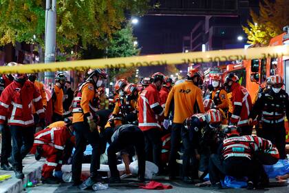Socorristas y bomberos trabajan en la escena de una estampida fatal en Seul, Corea del Sur, durante celebraciones de Halloween, el sábado, 29 de octubre del 2022. Al menos 120 personas murieron, dijeron las autoridades.  (Lee Ji-eun/Yonhap via AP)