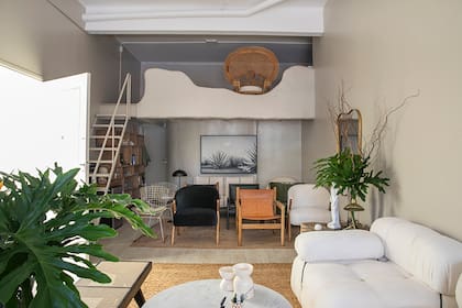 Sofá 'Camaleonda' de dos módulos de 95x95 tapizado en bouclé de algodón off-white. Mesa 'Olivia' con base de mármol de Carrara y patas en petiribí. Banco 'Pierre' en laca negra y esterilla de ratán.