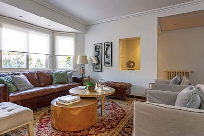 Sofá de cuero (Landmark). Almohadones ‘Velvet’ (Rapsodia Home) y puf capitoné. Lámpara de mesa ‘Wolverine’ (30quarenta). Cuadros de Adrian Lirman. Sillones individuales y mesas ‘Pergamino’ (Harturo).