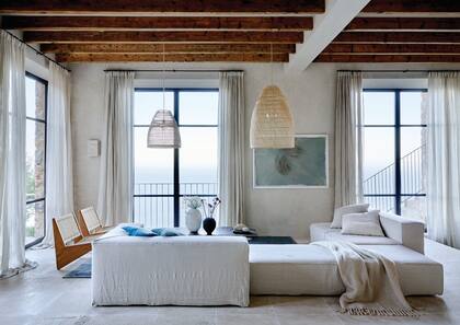 Sofá modular en lino, pantallas de fibras naturales y sillas de madera con respaldo de tiento de More Decor, el brazo de interiorismo del Estudo a cargo de la reforma. Cuadro de Guillem Nadal