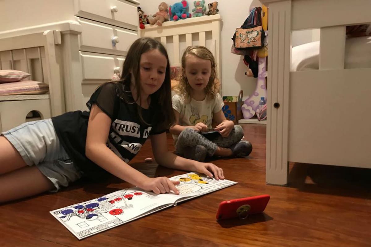 Sofia, de 9 años, y Catalina, de 3, leen un cuento ilustrado siguiendo la narración de la historia por la web