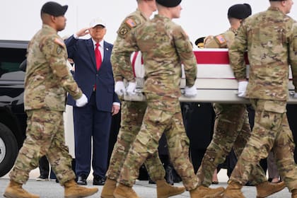 Soldados cargan un féretro que lleva los restos de la sargento de primera clase Nicole Amor, quien murió por un ataque de dron en un centro de mando de Kuwait durante la guerra de Estados Unidos e Israel en contra de Irán, mientras el presidente Donald Trump observa la llegada de los restos, el sábado 7 de marzo de 2026, en la Base de la Fuerza Aérea Dover, en Delaware.