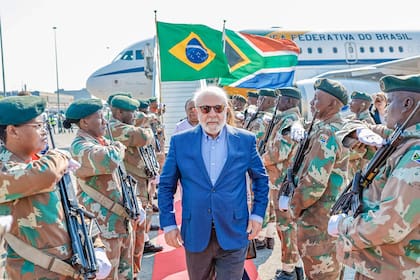 Soldados de la Fuerza de Defensa Nacional Sudafricana (SANDF) hacen guardia de honor a la llegada del presidente de Brasil, Luiz Inácio Lula da Silva (C), al aeropuerto internacional OR Tambo de Ekurhuleni el 21 de agosto de 2023, antes de la Cumbre de los BRICS de 2023