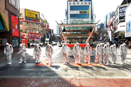 Soldados del ejército de Corea del Sur con trajes protectores rocían desinfectante para evitar la propagación del coronavirus en una calle de Daegu, Corea del Sur