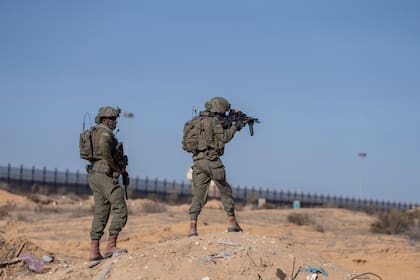 Soldados israelíes apuntan con un arma al montar guardia en el laso palestino del cruce fronterizo de Kerem Shalom durante un recorrido de periodistas por el área de la Franja de Gaza, el 19 de diciembre de 2024. (AP Foto/Ohad Zwigenberg)