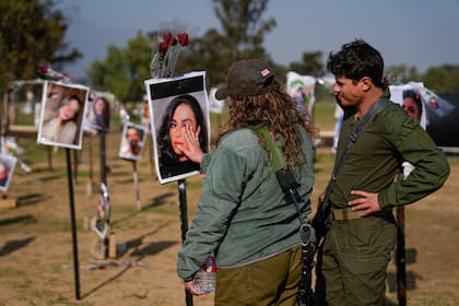 Soldados israelíes observan fotos de las víctimas del ataque de Hamas al festival Nova en el sur de Israel, exhibidas en el lugar de los hechos para conmemorar la masacre del 7 de octubre