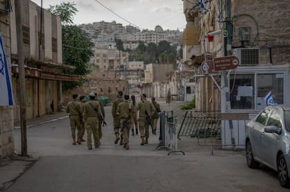 Soldados israelíes pasan por la puerta de Fawaz Qafisha. Los residentes palestinos no tienen permitido salir a la calle.