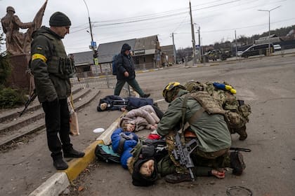 Soldados ucranianos intentan salvar al padre de una familia de cuatro integrantes, el único que todavía tenía pulso momentos después de ser alcanzado por un mortero mientras intentaba huir de Irpin, cerca de Kiev, Ucrania, el domingo 6 de marzo de 2022.