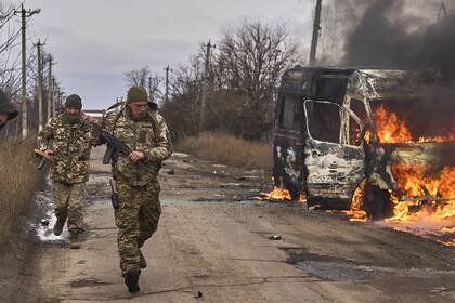 Soldados ucranianos pasan junto a un ómnibus de voluntarios en llamas después de que un dron ruso lo impactara cerca de Bakhmut, región de Donetsk, Ucrania (Shandyba Mykyta, Ukrainian 10th Mountain Assault Brigade "Edelweiss" via AP, File)