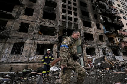 Soldados y bomberos ucranianos buscan en un edificio derruido tras un ataque en Kiev, Ucrania, el lunes 14 de marzo de 2022