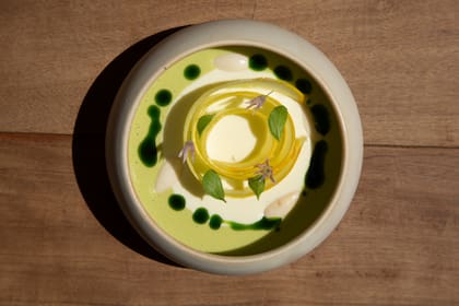 Sopa fría de espárragos y almendras, con zuchini amarillo, peperina, flores de ciboulette, almendras y aceite de perejil.