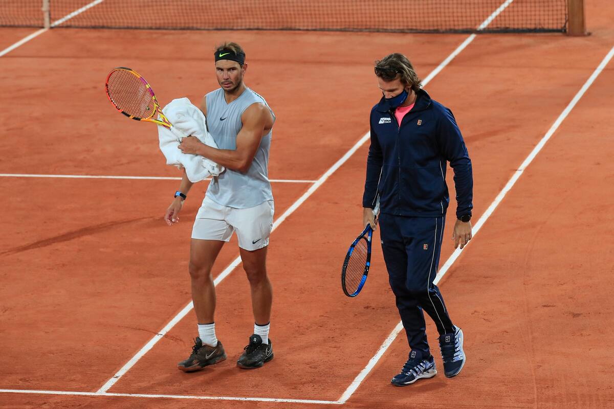 Spains Rafael Nadal, left, and his coach Francisco Roig wearing a face mask to prevent the spread of coronavirus walk on the clay during practicing at the Roland Garros stadium in Paris, Friday, Sept. 25, 2020