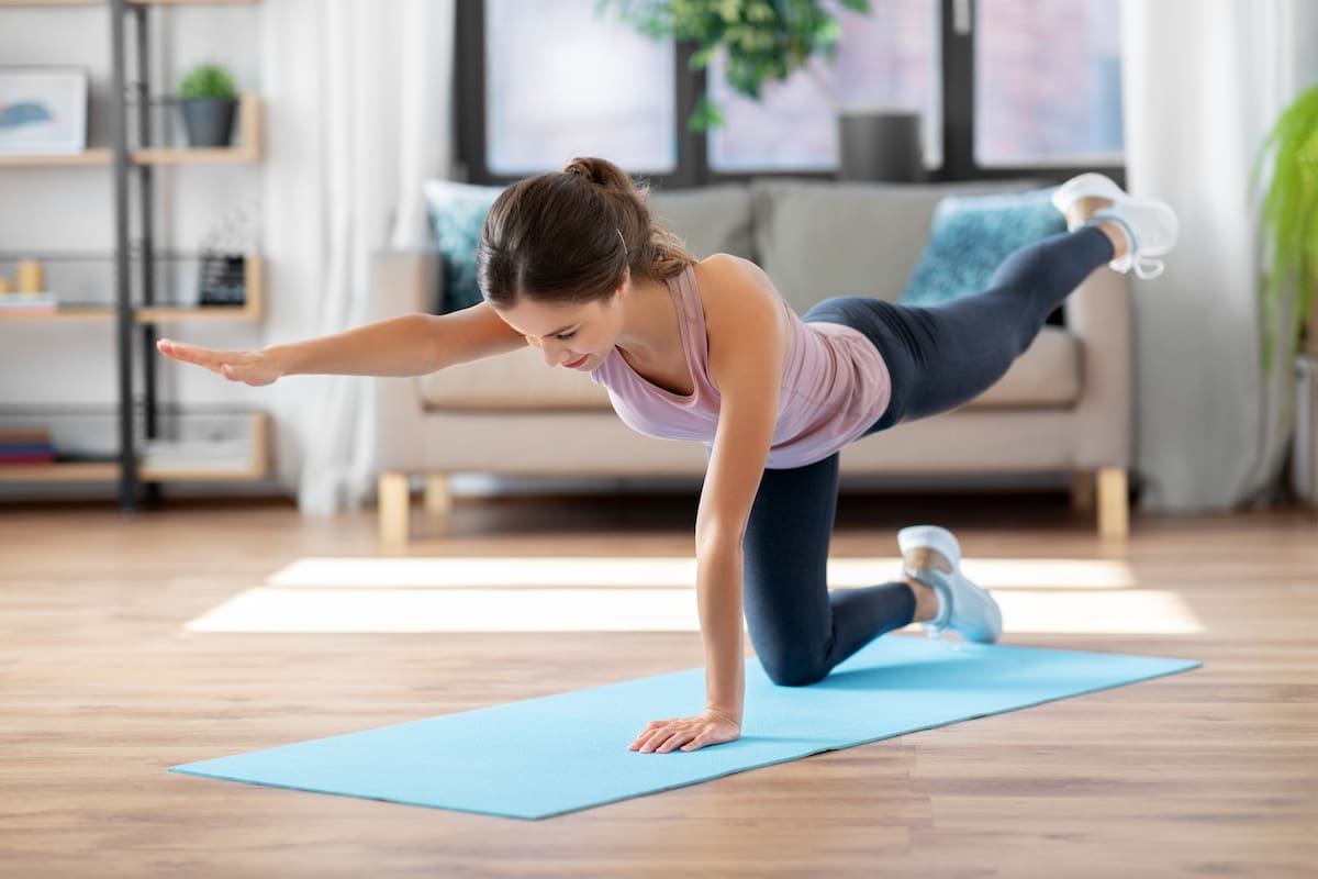 sport, fitness and exercising concept - happy young woman doing elbow knee crunches at home