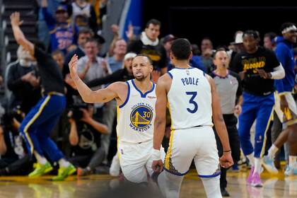 Stephen Curry (30), de los Warriors de Golden State, recibe la felicitación de su compañero Jordan Poole (3) tras anotar contra los Nuggets de Denver en la primera mitad del segundo juego de su serie de primera ronda del playoff en San Francisco, el 18 de abril de 2022. (AP Foto/Jeff Chiu)
