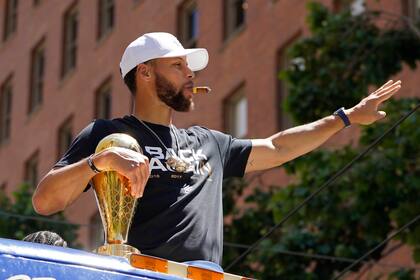 Stephen Curry fuma un puro y saluda a la afición en el desfile tras ganar el título de la NBA con los Warriors; la estrella de la NBA será el jugador mejor pago en la temporada 2022/23