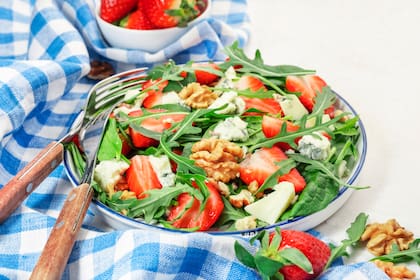Strawberry Salad with spinach, arugula, walnuts, blue cheese on gray table. Healthy food. Top view