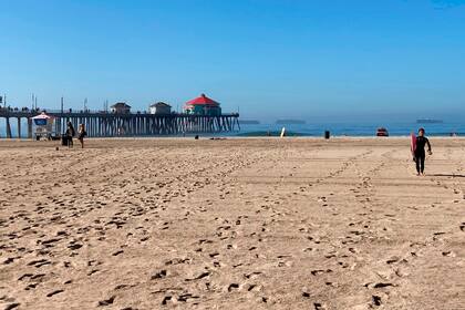 Surfistas salen del agua en una playa de Huntington Beach, California, el 10 de octubre de 2021. La playa, que se cerró hace más de una semana debido a una fuga en un oleoducto submarino reabrió el 11 de octubre. (AP Foto/Amy Taxin)