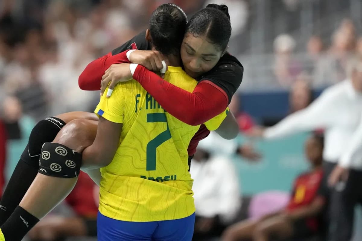 Tamires Araujo de Brasil lleva en brazos a su rival Albertina Kassoma de Angola, durante un partido de balonmano en París 2024
