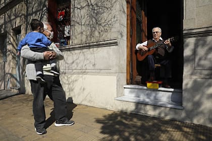 El Tata Cedrón toca su música para los vecinos desde el zaguán de su casa, en Villa del Parque