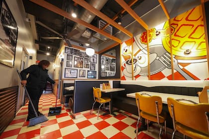 Teaira Booker barre el piso del restaurante The Breakfast Brothers frente a un mural con platillos del desayuno, el miércoles 12 de febrero de 2025, en Arlington, Texas. (AP Foto/Julio Cortez)