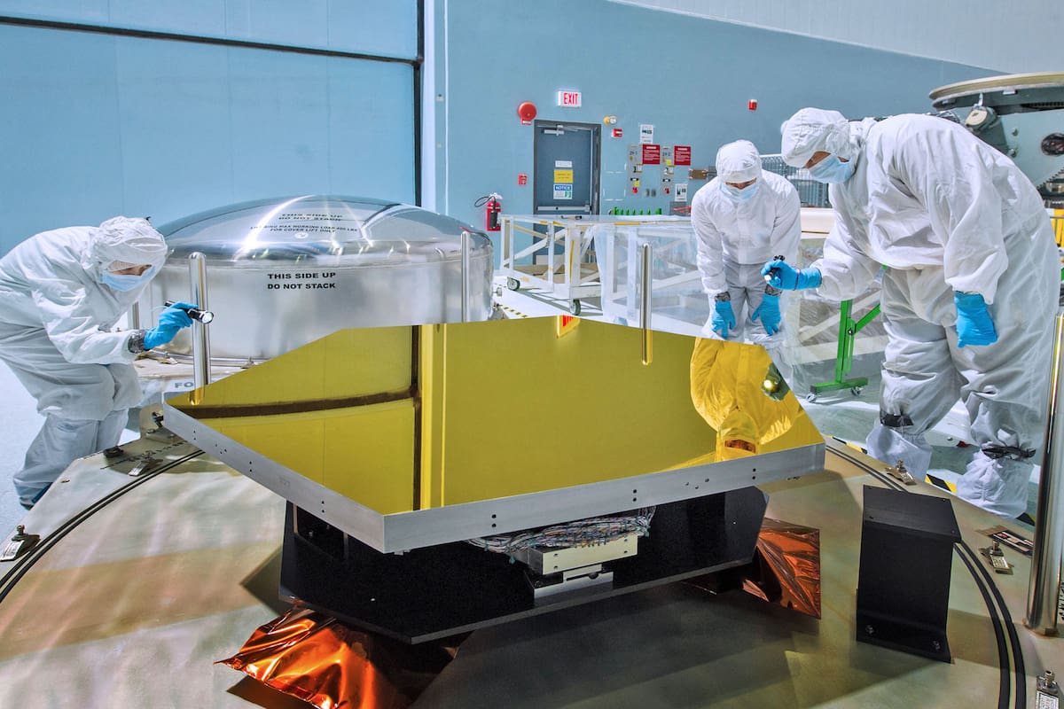 Técnicos e investigadores verifican uno de los dos espejos del telescopio Webb en una sala limpia del Goddard Space Flight Center