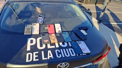 Teléfonos recuperados durante el operativo en Costanera Norte, exhibidos sobre el capó de un móvil policial