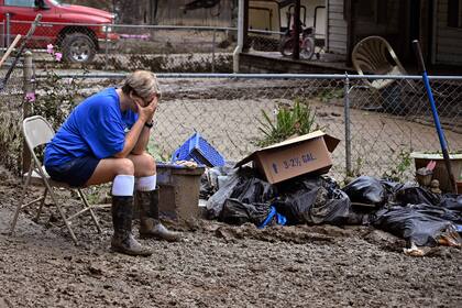 Teresa Reynolds se sienta exhausta mientras miembros de su comunidad despejan los escombros de casas destruidas por inundaciones en Ogden Hollar, Kentucky, el 30 de julio del 2022.  (AP Foto/Timothy D. Easley)
