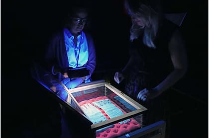 Tessa Gadomski (izquierda), bibliotecaria de conservación, y Alicia Meyer (derecha), curadora de servicios de investigación de las Bibliotecas, examinando los legendarios guantes con luz ultravioleta