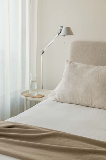 Textiles etéreos, mesas de luz simples y una lámpara Tolomeo que dialoga con los elementos y las obras que están en el living.