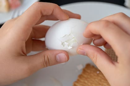 The boy is cleaning the egg with her hands, close up. Hands peeling boiled egg.