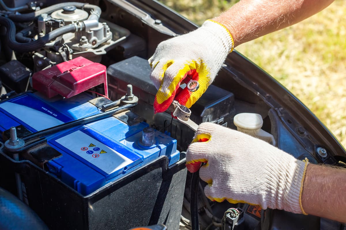 The car mechanic unscrews the car battery holder to repair or replace it. Transport service.