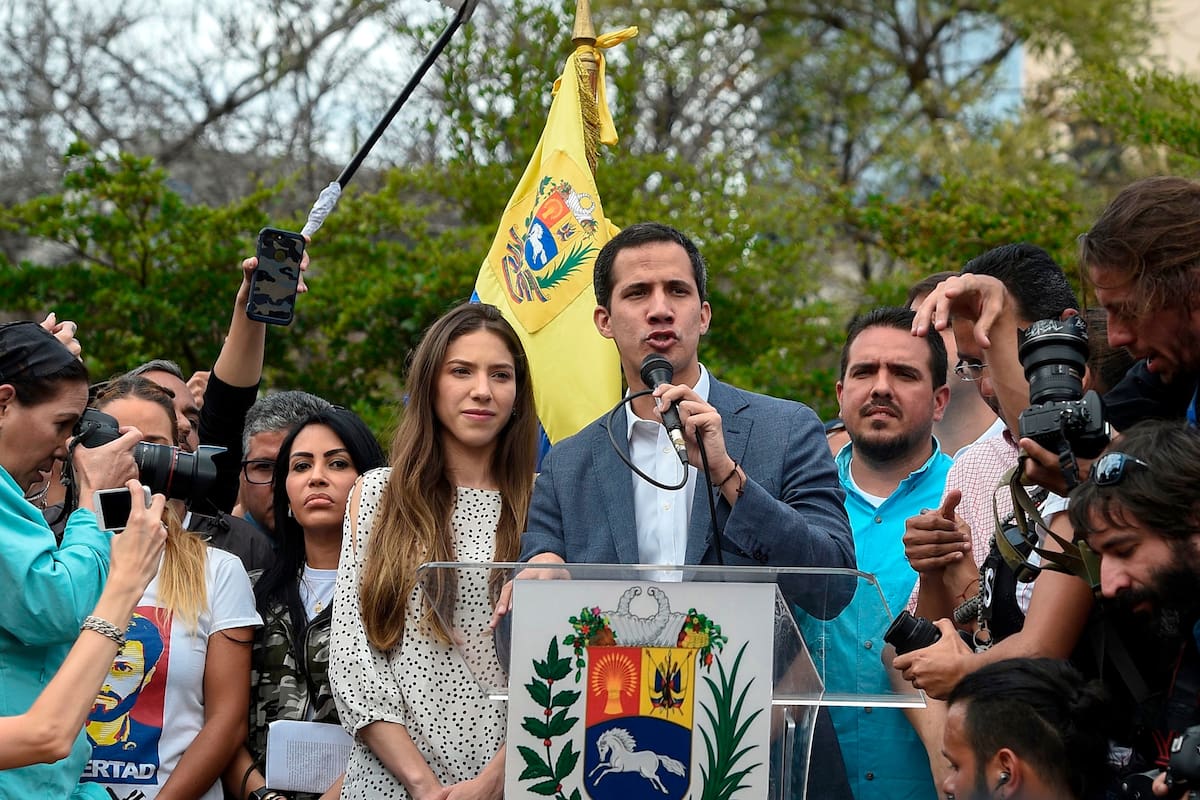 The head of Venezuelas National Assembly and the countrys self-proclaimed "acting president" Juan Guaido (C), accompanied by his wife Fabiana Rosales (C-L), gestures before a crowd of opposition supporters during a rally in Caracas, on January 26, 2019. (Photo by Federico PARRA / AFP)