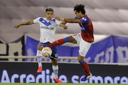 Thiago Almada, quien debió retirarse del campo por un problema muscular, pelea por la pelota con Ignacio Saavedra, de Universidad Católica.