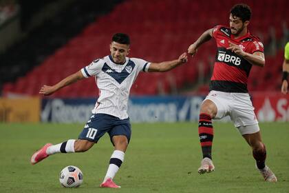 Thiago Almada, enganche de Vélez, remata al arco sin que el central Gustavo Henrique lo pueda evitar; un empate 0-0 con Flamengo que le impidió al equipo de Mauricio Pellegrino finalizar primero en su zona