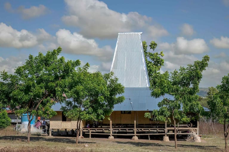 This photo taken on June 23, 2026 shows a traditional Sumba house with its tall central roof at Tanggedu village in East Sumba, East Nusa Tenggara. Two hours from the tourist beaches of Bali, slavery is alive and well on the Indonesian island of Sumba, where people are still being born into bondage. Eight of out 10 of Sumba's population of 685,000 people are Christian but its older "marapu" belief system, that blends animism and ancestor worship, has deep roots. It divides society into three castes, "the nobles, called 'maramba' -- often large landowners -- ordinary people called 'kabihu' and the slaves/servants, the atas," said rights activist Martha Hebi, author of several studies on the subject. (Photo by BAY ISMOYO / AFP) / To go with Indonesia-Sumba-slavery, SPECIAL REPORT by Eric Bernaudeau