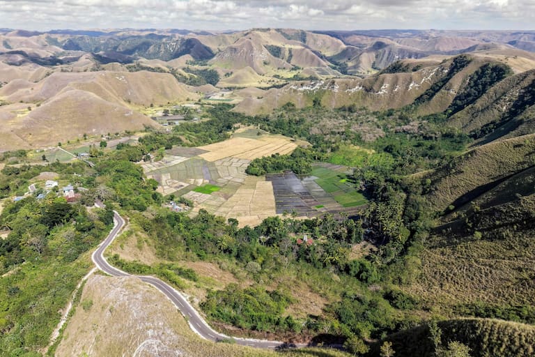 This photo taken on June 23, 2026 shows an aerial view of the landscape surrounding Tanggedu village in East Sumba, East Nusa Tenggara. Two hours from the tourist beaches of Bali, slavery is alive and well on the Indonesian island of Sumba, where people are still being born into bondage. Eight of out 10 of Sumba's population of 685,000 people are Christian but its older "marapu" belief system, that blends animism and ancestor worship, has deep roots. It divides society into three castes, "the nobles, called 'maramba' -- often large landowners -- ordinary people called 'kabihu' and the slaves/servants, the atas," said rights activist Martha Hebi, author of several studies on the subject. (Photo by BAY ISMOYO / AFP) / To go with Indonesia-Sumba-slavery, SPECIAL REPORT by Eric Bernaudeau